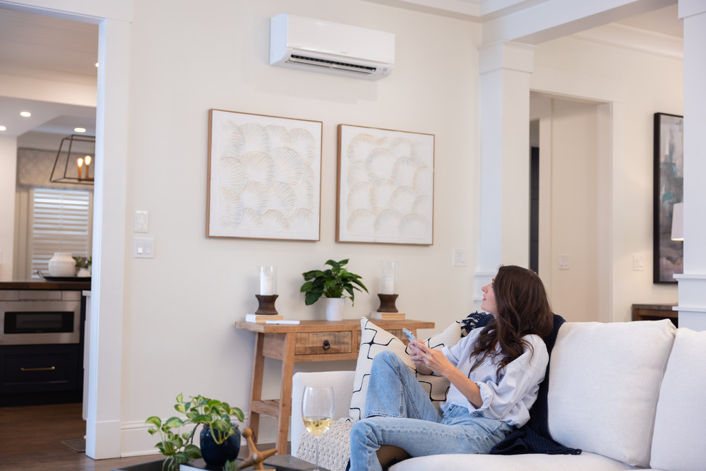 Woman relaxing on couch with ductless mini-split cooling system